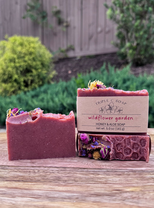 Three bars of red soap topped with dried flowers with Triple C Soap label.