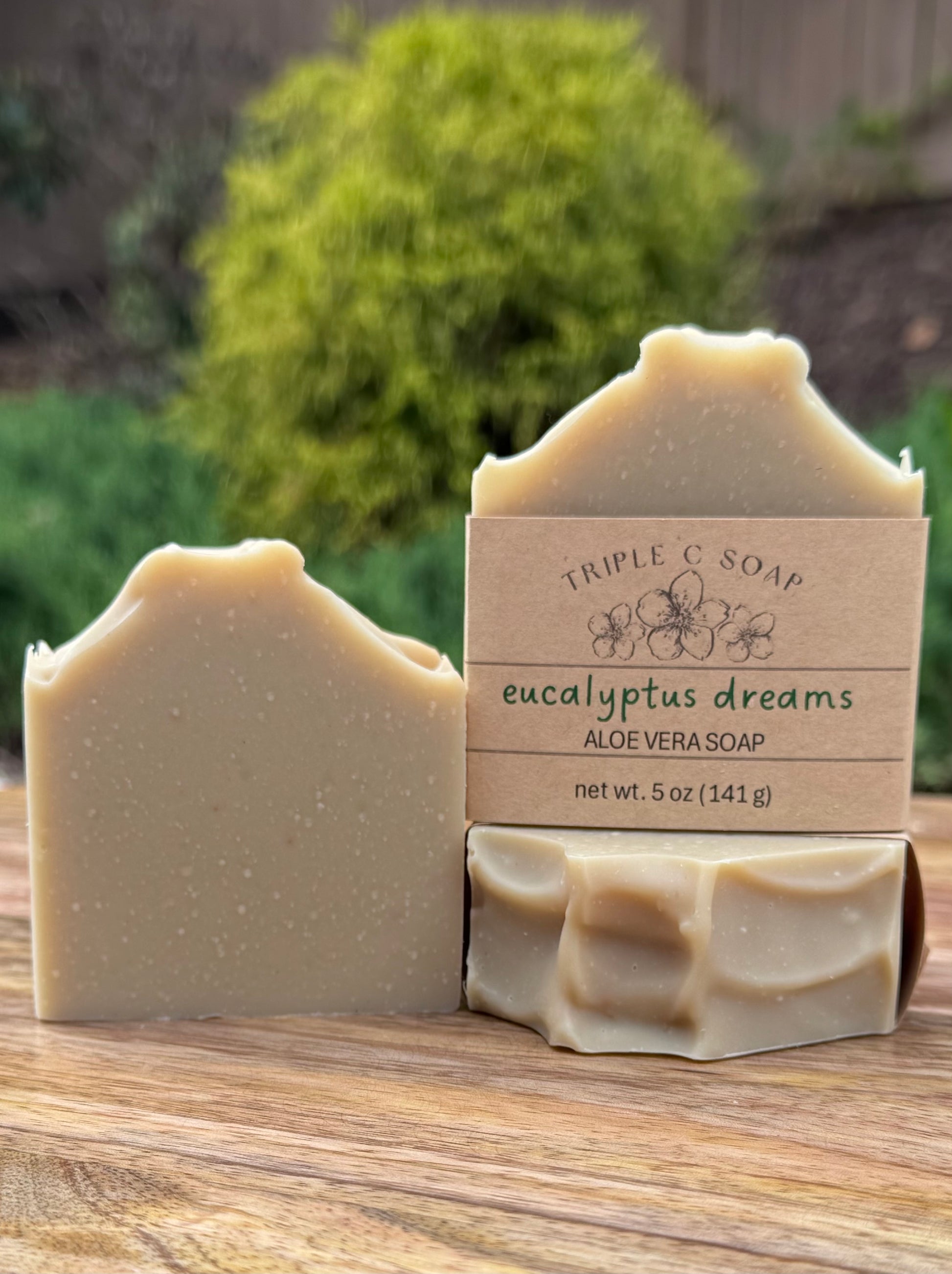 Three bars of aloe vera soap with a 'Triple C Soap Eucalyptus Dreams' label on a wooden surface.
