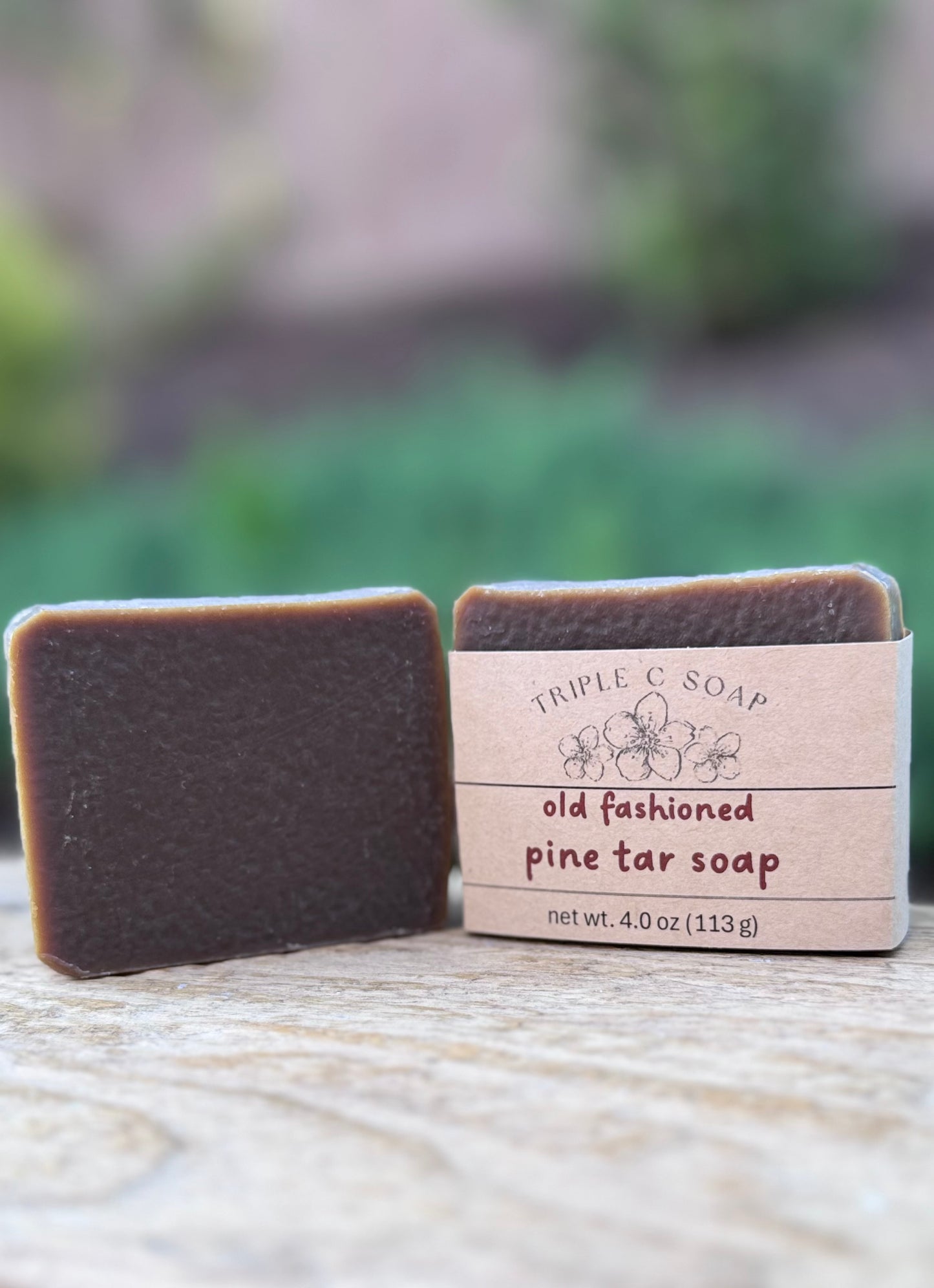 Three bars of old fashioned pine tar soap with a label on a wooden surface outdoors