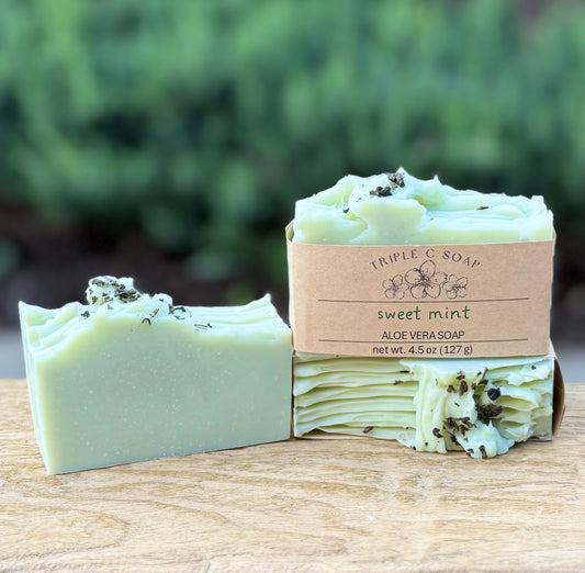 Three bars of sweet mint aloe vera soap on a wooden surface.