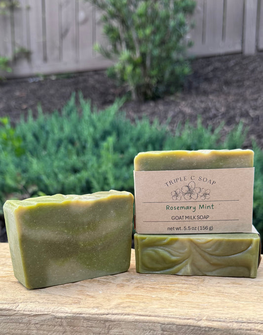 Three bars of Rosemary Mint goat milk soap on a wooden surface