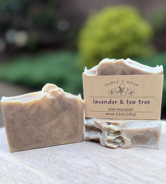 Three bars of lavender and tea tree soap on wooden surface outside.