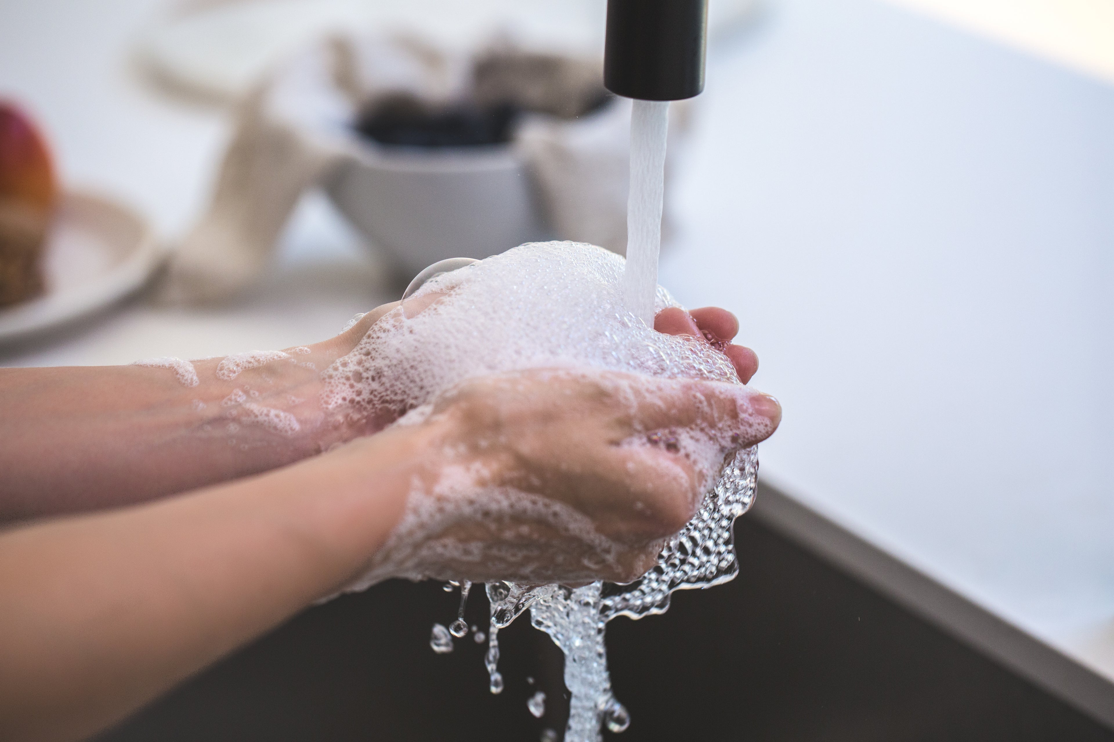 Someone washing their hands at a kitchen sink